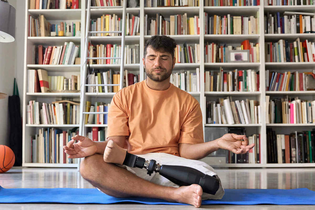Man with an above the knee amputation sitting down on the floor doing yoga