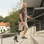 smiling man walking up the stairs outside wearing his advanced microprocessor foot Photo-Ottobock