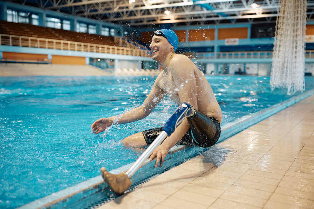 Swimming athlete with an above the knee amputation sitting splashing the water between laps
