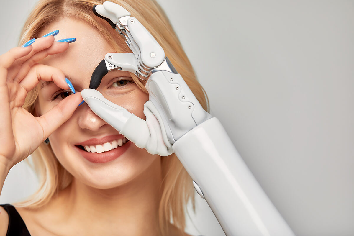 Smiling woman with an advanced prosthetic arm and hand standing in a studio