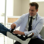 Smiling doctor adjusting an ankle foot orthosis in the hospital
