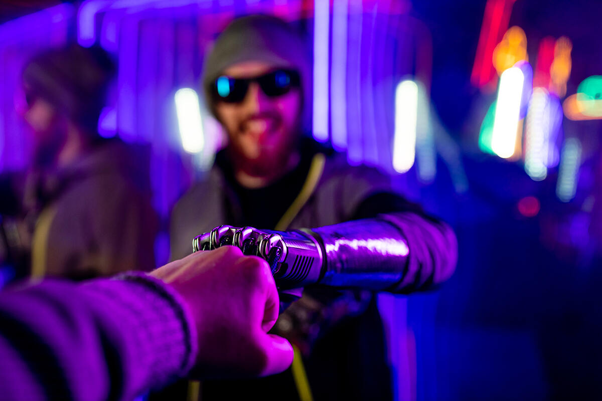 Smiling cool looking man in a nightclub wearing sunglasses and his advanced robotic prosthetic arm