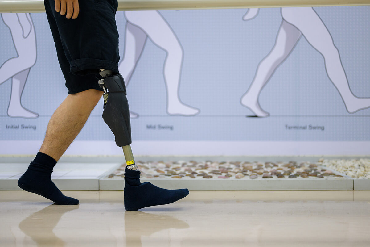 Person walking indoors with an above the knee amputation wearing an advanced knee and leg prosthetic