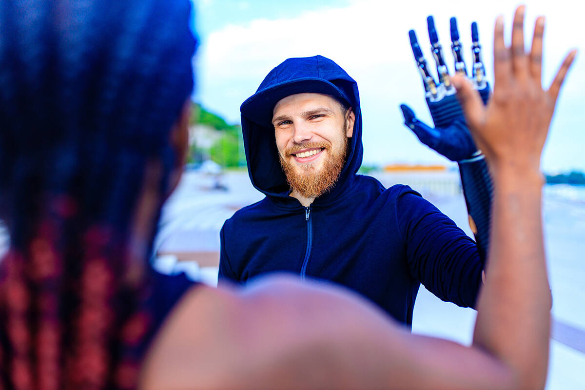 Smiling man with an prosthetic arm and hand greeting a friend outdoors