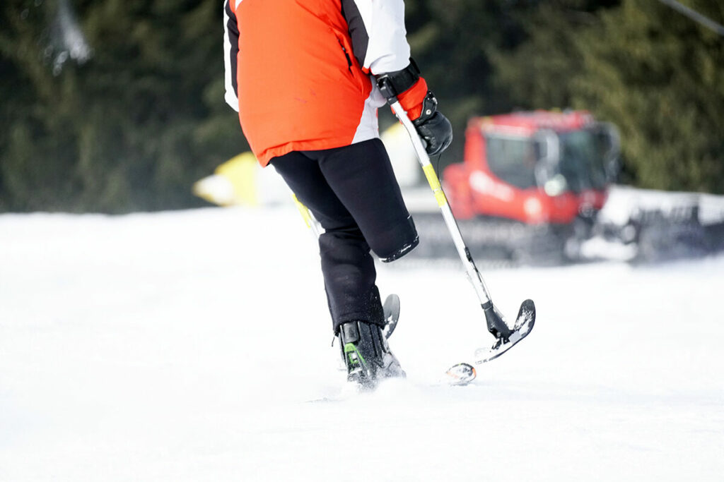 Person with a leg amputation skiing with special skiing equipment on a sunny day