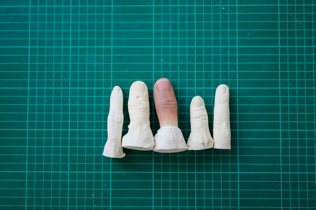 5 different prosthetic silicone fingers in different process showing the process of creating prosthetic fingers