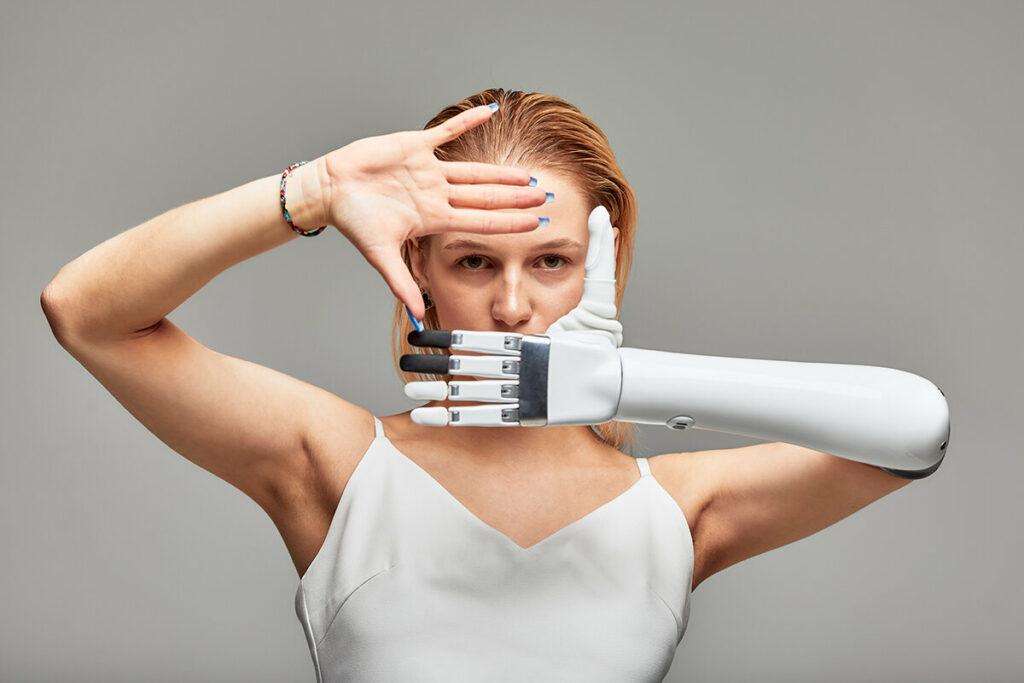 Focused woman standing against a white background wearing her bionic advanced hand and arm