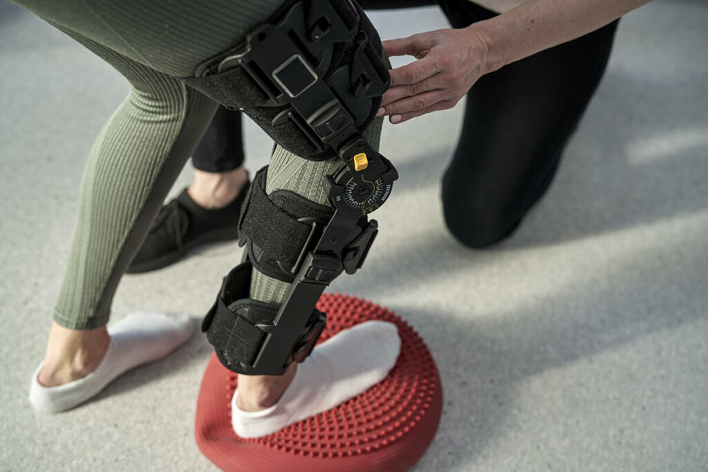Female wearing a leg brace working out with a personal trainer