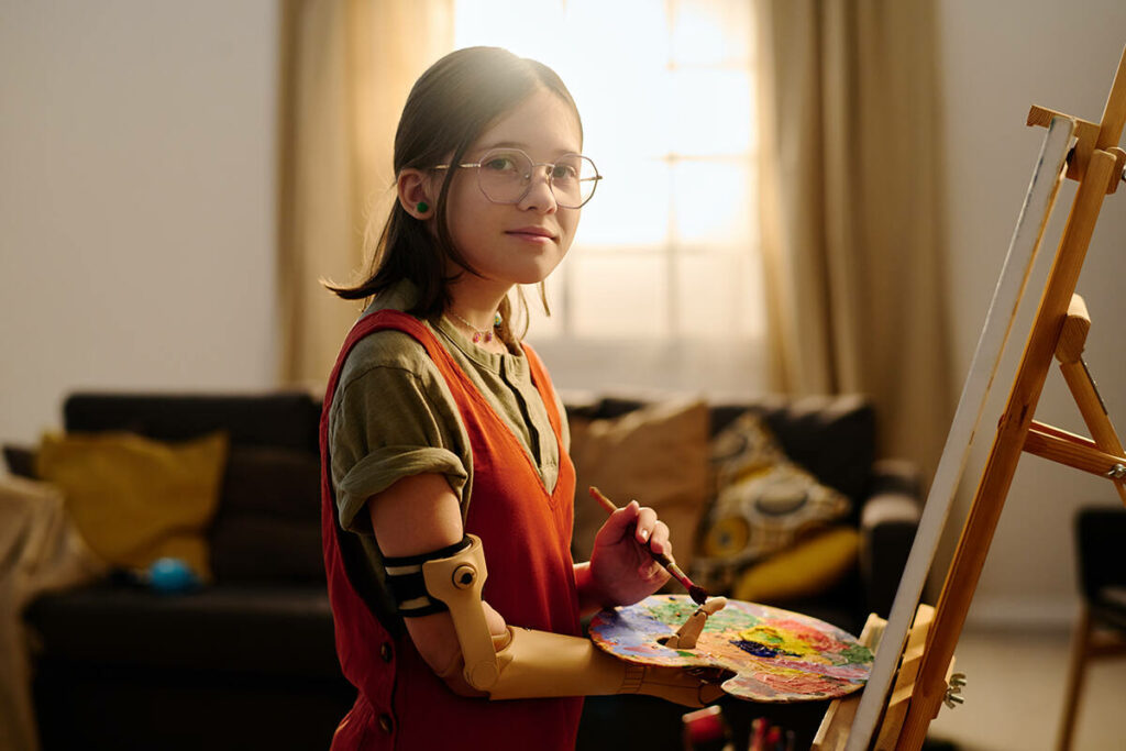 Female working on her art indoors wearing an advanced robotic arm and hand