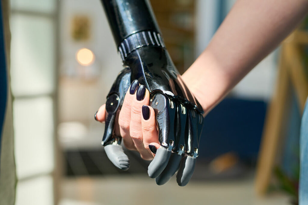 An advanced robotic hand with fingers holding a human hand indoors
