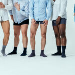 Group of men standing in a studio wearing shirt and underwear talking about testicular prosthesis