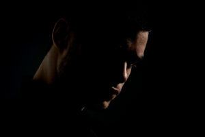 person with face prosthetics covering himself in the shadows