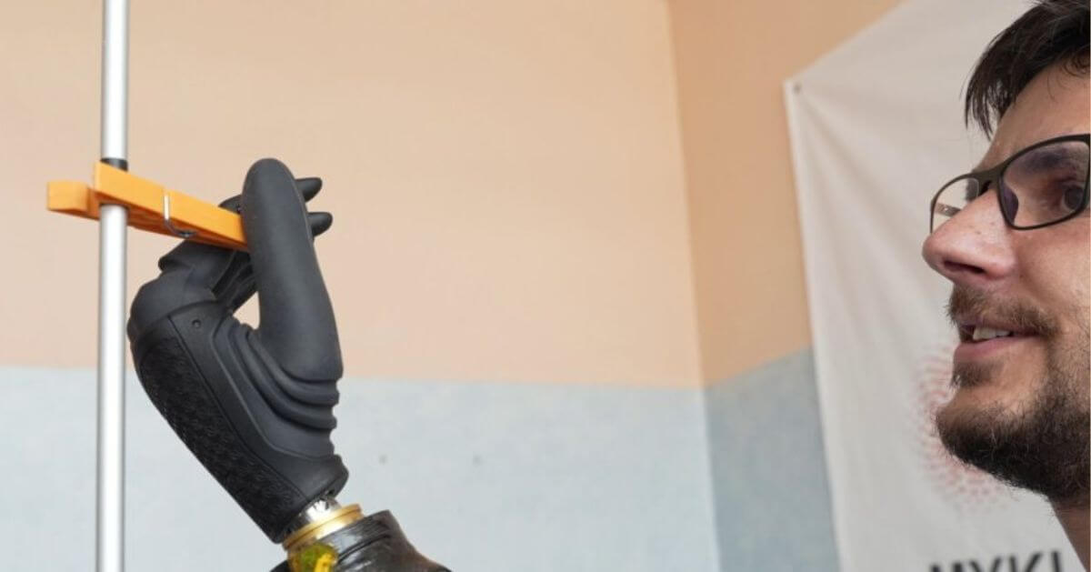 Close-up of a man using the magnet-controlled prosthetic hand to grip an orange clip