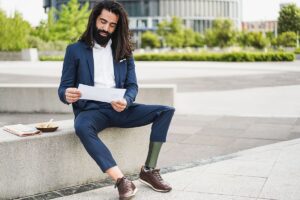 Business professional with a prosthetic leg sitting outdoors and reviewing a paperwork.