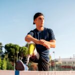 Athlete with a lower-leg prosthetic stretching outdoors during training.