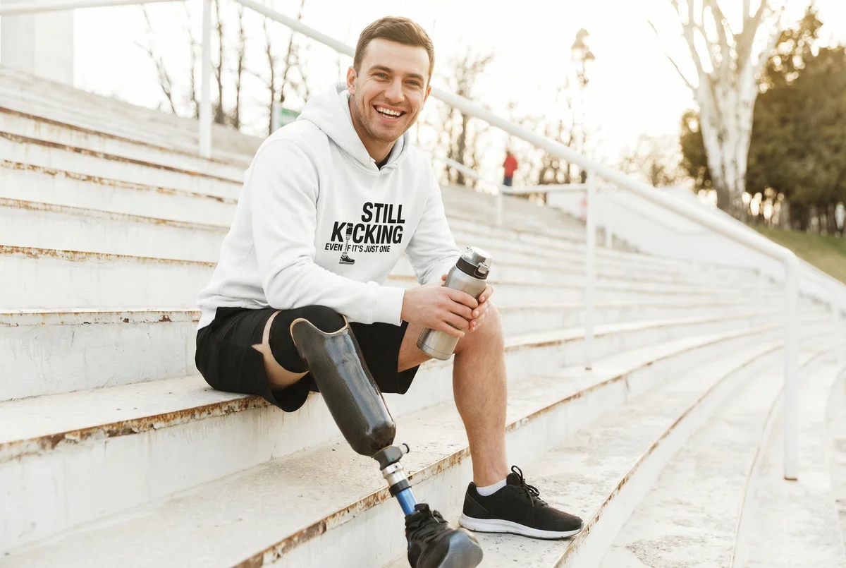 Man on bleachers wearing IsBrave Still Kicking hoodie