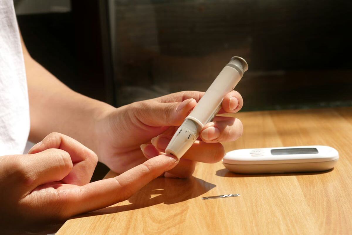 Person using a glucose meter to check blood sugar levels with a finger prick test for diabetes management.
