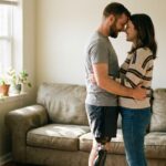 Amputee couple embracing closely at home, man wearing a below-knee prosthetic leg