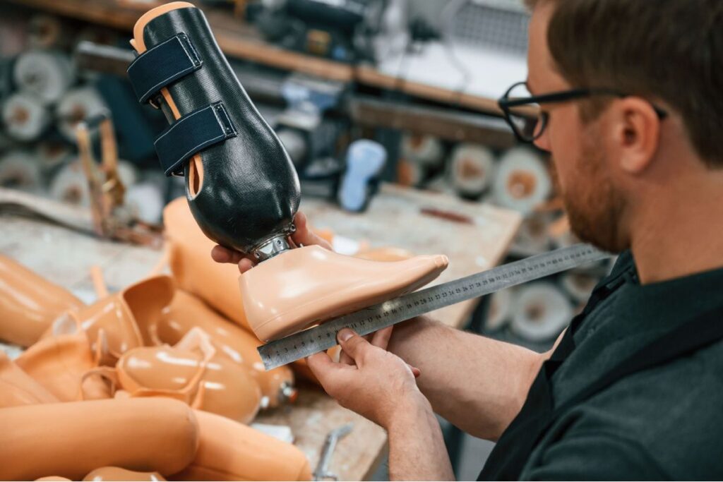 Technician measuring a lower-limb prosthetic foot in a prosthetics workshop.