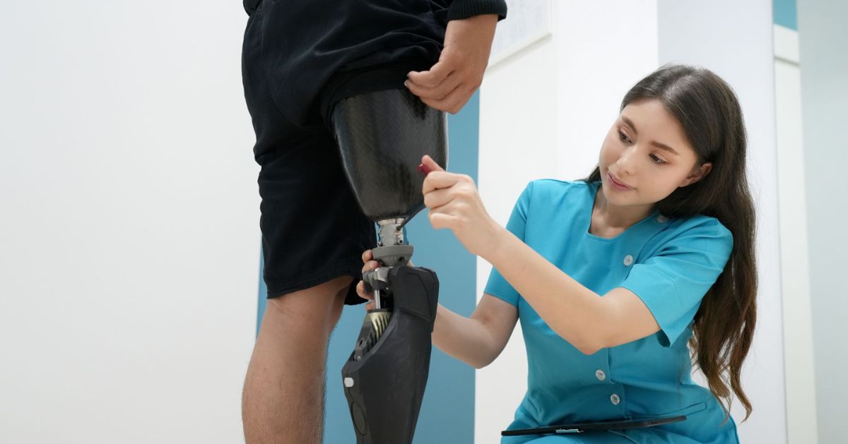 Prosthetist adjusting the alignment of a above-knee prosthetic leg during a fitting appointment in a prosthetics clinic.