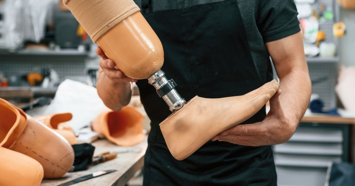 Prosthetist holding a prosthetic leg during assembly in a prosthetics workshop.