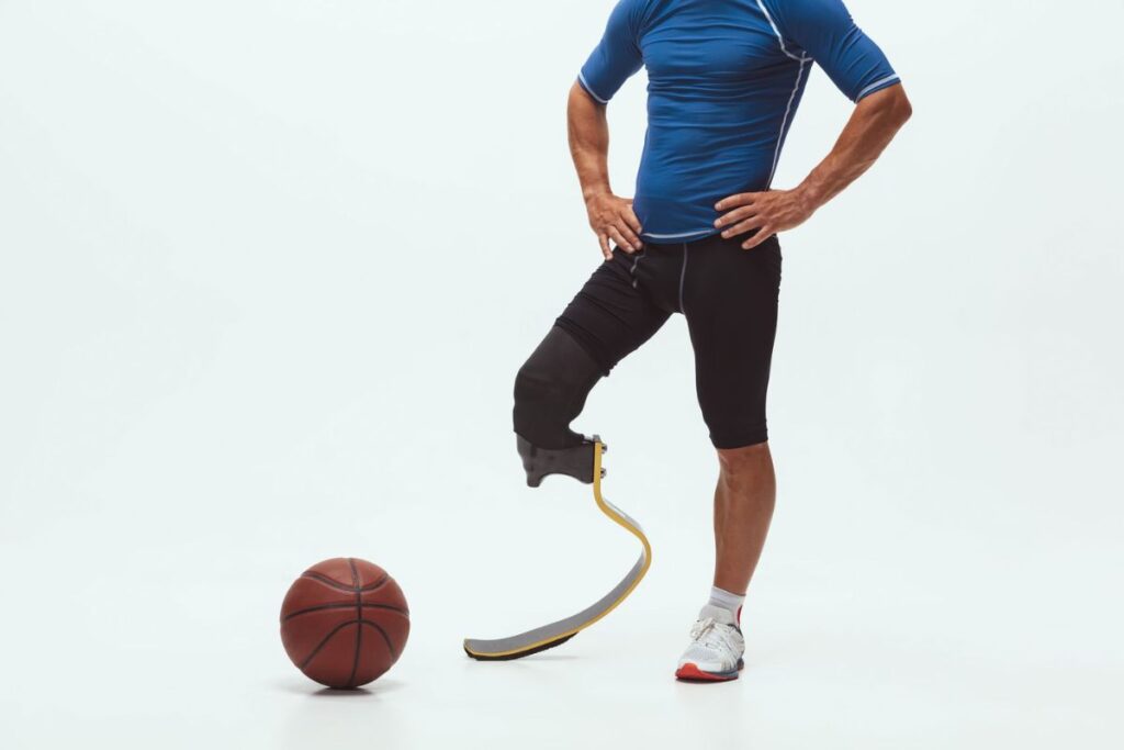 Below-knee amputee athlete wearing a running blade standing beside a basketball.