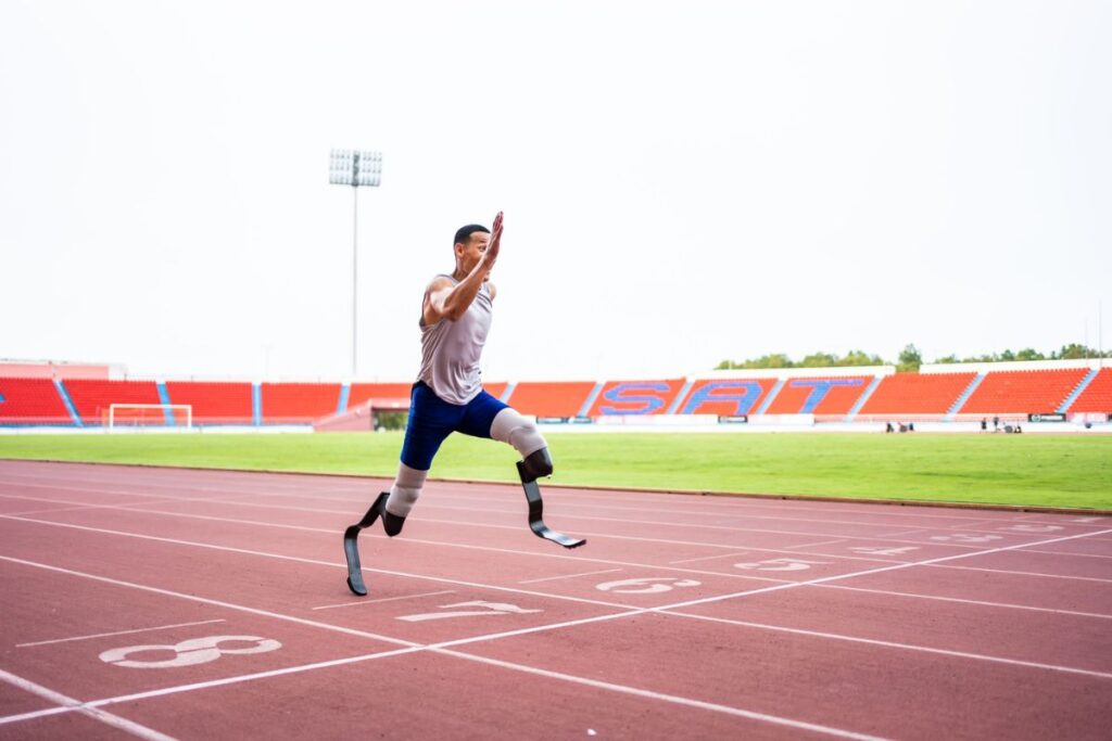Bilateral below-knee amputee athlete sprinting on a running track with prosthetic running blades.