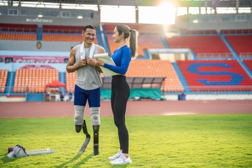 Bilateral below-knee amputee athlete talking with a coach on a running track