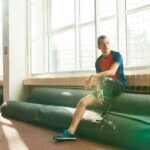Man with a prosthetic leg resting after exercise at an indoor gym.